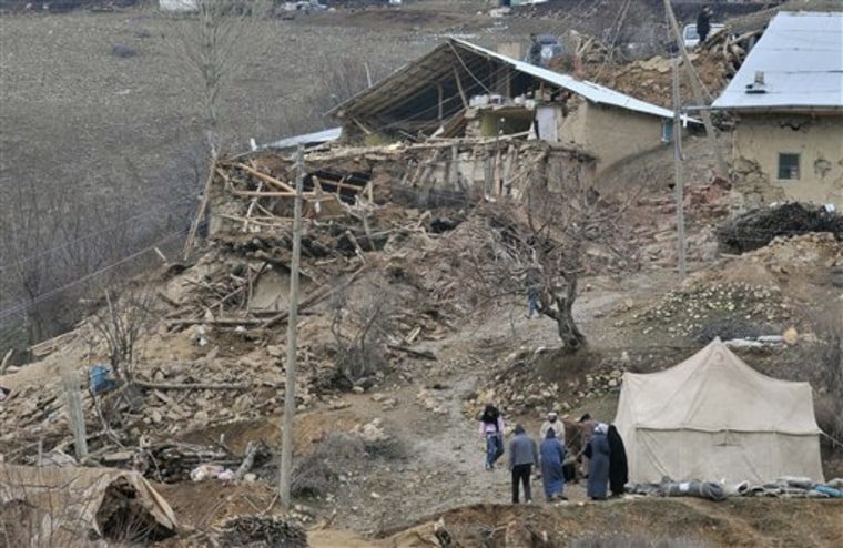 People walk in the debris of houses destroyed in an earthquake in the eastern province of Elazig, Turkey, Monday, March 8, 2010. Scientists say there is no direct connection between the lethal quakes that have struck Haiti, Chile and Turkey. 